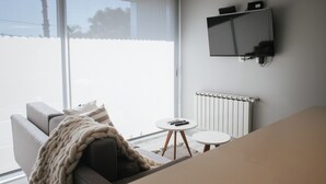 A modern living room with a sofa, a TV mounted on the wall, and a small round table.