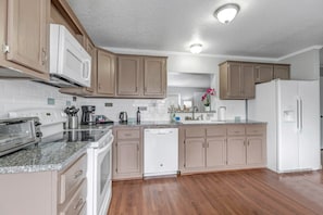 A kitchen with a microwave, toaster, coffee maker, dishwasher, and a refrigerator. - Mile High 5BR Escape – Walk To Shops | Sleeps 13 (Arvada)