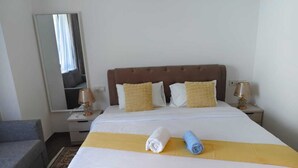 Une chambre d’hôtel avec un lit, deux lampes de chevet, un miroir et une petite table.