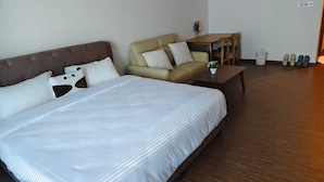 Une chambre d’hôtel avec un grand lit, un canapé, une petite table et une poubelle.