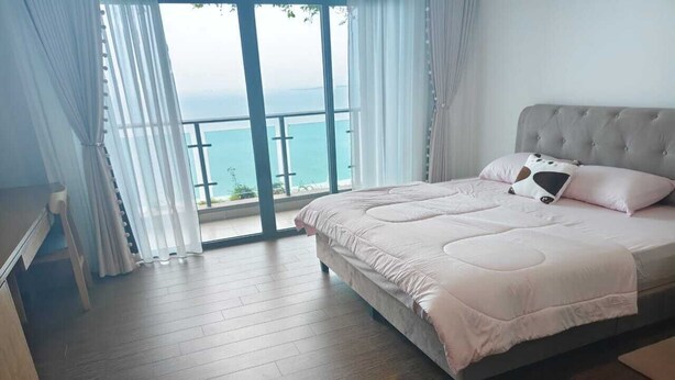 Une chambre avec un grand lit, une vue sur la mer et un balcon.