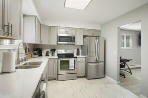 A modern kitchen with stainless steel appliances, a microwave, oven, and refrigerator, and a white countertop. - 2BR Wheat Ridge Home| Near Denver, Golden and I-70 (Wheat Ridge)