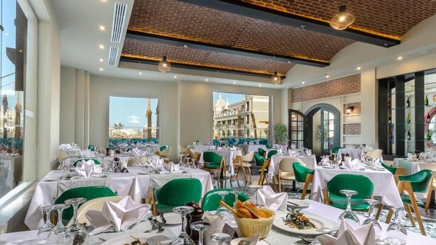 A restaurant with tables set for dining, green chairs, and a brick ceiling. - Titanic Royal Palace (Hurghada)