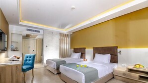 A hotel room with two beds, a desk, a chair, and a TV. - Titanic Royal Palace (Hurghada)
