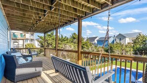 A covered deck with a swing, a sofa, and a view of a swimming pool. - Pirates & Paradise: Private Pool, Home Theatre, and Pet Friendly (Surf City)