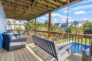 A covered deck with a swing, a sofa, and a view of a swimming pool. - Pirates & Paradise: Private Pool, Home Theatre, and Pet Friendly (Surf City)