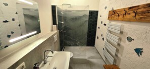 A bathroom with a glass shower enclosure, a white sink, and a mirror with a light. - Hof Hauswang (Pfronten)