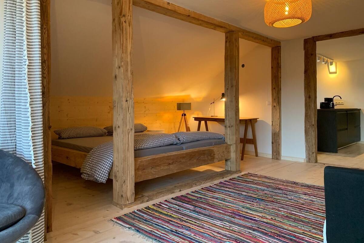 Une chambre à coucher de style rustique, avec un lit en bois, un bureau et un coin cuisine.