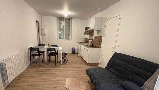 Een kleine leefruimte met een eethoek, kitchenette en een bank.