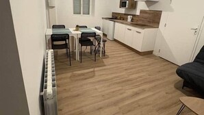 Een kleine keuken met een eethoek, een magnetron en een koelkast.