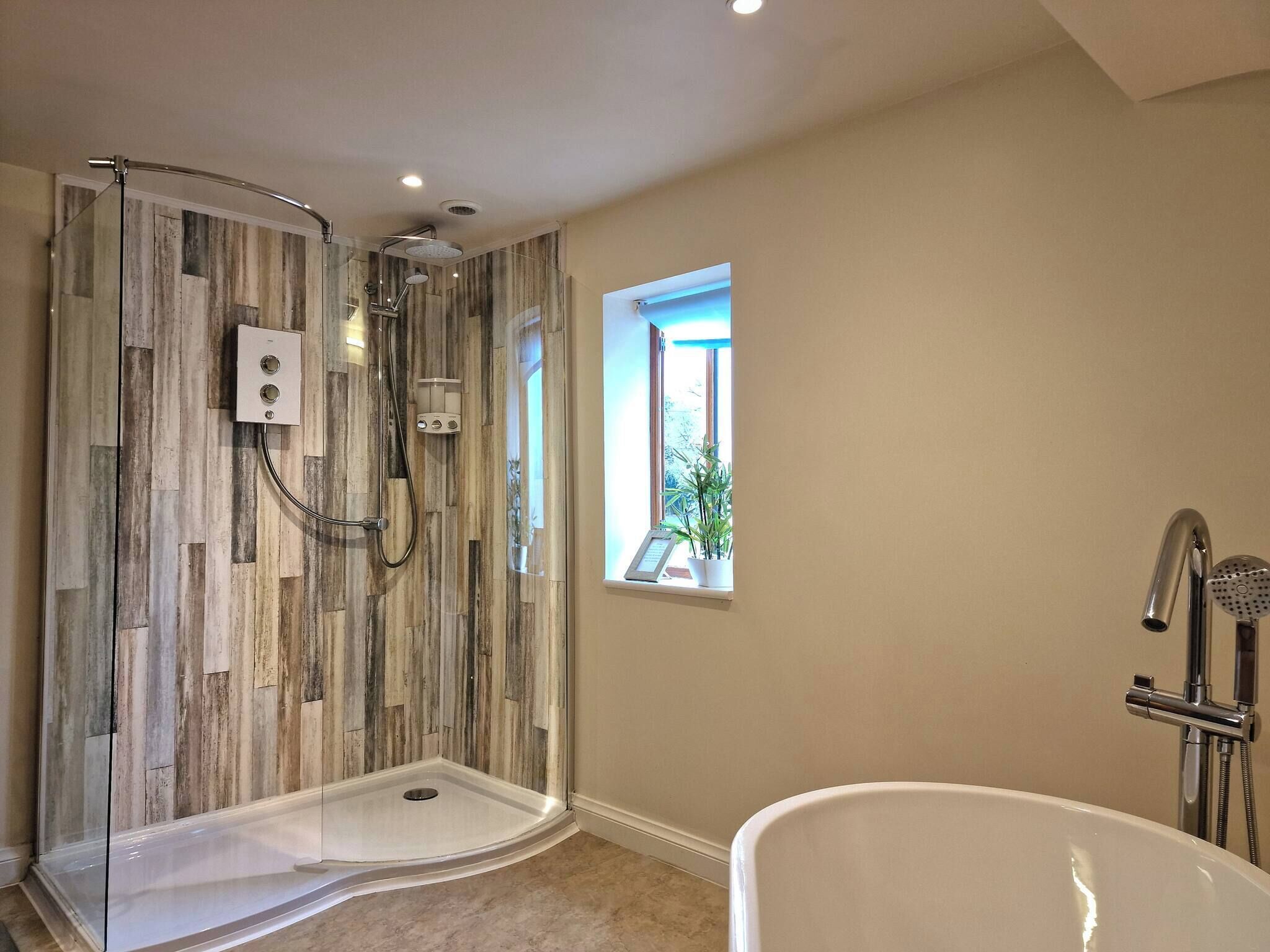A bathroom with a walk-in shower, a bathtub, and a window with a view.