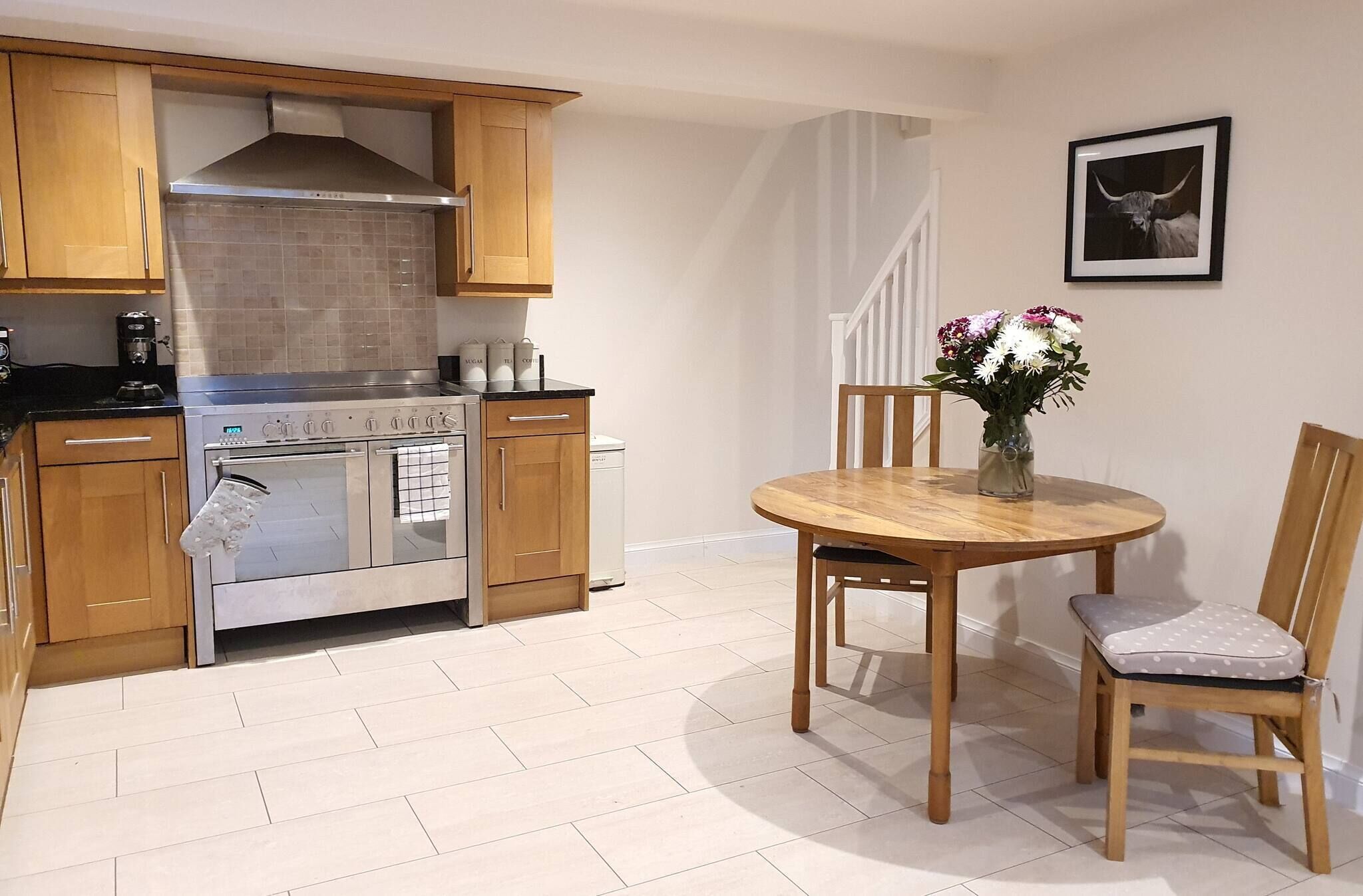 A kitchen with wooden cabinets, a stainless steel stove, and a dining area with a wooden table and chairs.