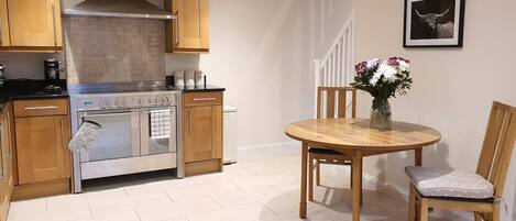 A kitchen with wooden cabinets, a stainless steel stove, and a dining area with a wooden table and chairs.
