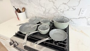 A kitchen with a stove, pots, pans, and a marble backsplash. - New 2BR/2BA LUXE Harvard & MIT w/Parking Red Line (Somerville)