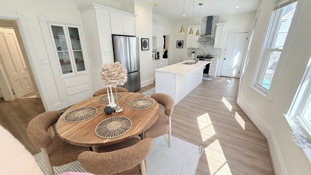 A modern kitchen with white cabinetry, a stainless steel refrigerator, and a central island. - New 2BR/2BA LUXE Harvard & MIT w/Parking Red Line (Somerville)