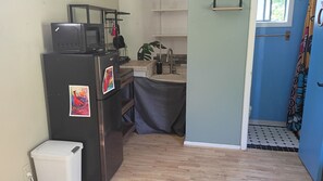 Een kleine keuken met een koelkast, magnetron en wastafel.