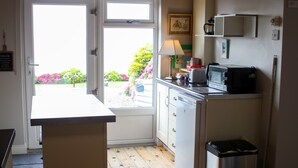 Une cuisine compacte avec une fenêtre, un four à micro-ondes, une poubelle et un petit placard.