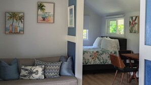 A modern interior with a sofa, a bed, a dining table, and artwork on the walls.