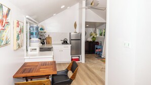 A compact kitchen with white cabinets, a wooden dining table, and a black chair.