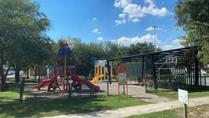 A playground with slides and climbing structures, surrounded by trees and a fenced area. - Loft en Distrito Tec. a 5 min a Fundidora. Walmart Nuevo Sur, Seguro y caminable (Monterrey)