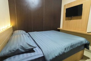 Ein Schlafzimmer mit Bett, Wandfernseher und Nachttisch.