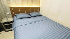 A bed with a headboard, a bedside table, and a wall socket. - J&L Inn Semarang (Semarang)