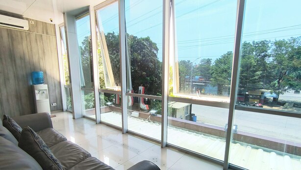 A modern hotel room with large windows, a water dispenser, and a sofa. - J&L Inn Semarang (Semarang)