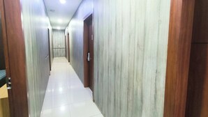 A hallway with wooden doors and a tiled floor. - J&L Inn Semarang (Semarang)