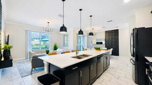 Una cucina moderna con una grande isola, mobili neri e illuminazione a sospensione.
