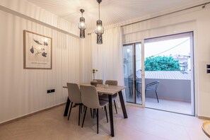 Ein Essbereich mit Tisch, Stühlen, Pendelleuchten, einer Blumenvase und einem gerahmten Bild an der Wand.