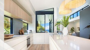 Una cocina moderna con un ventanal grande, horno empotrado y encimera blanca.