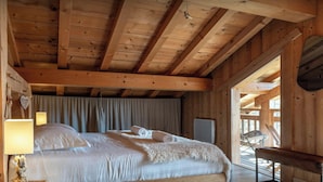 A wooden cabin room with a bed, a lamp, and a chair.