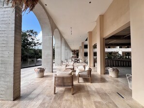 A covered outdoor area with seating, columns, and potted plants. - Elegant apartment with a jacuzzi, pool, and fitness room   (Tulum)