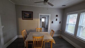 A dining room with a table and chairs, a ceiling fan, a framed picture, and a window with blinds. - New River Gorge Riverview Home in Meadow Creek.  3 bedroom, 1 bath, fenced yard (Meadow Creek)