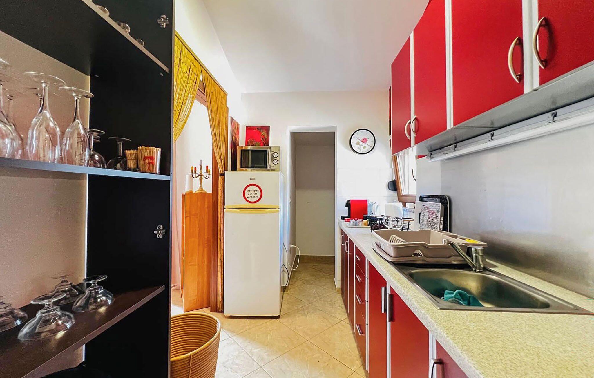 Une cuisine équipée d’un réfrigérateur, d’un four à micro-ondes, d’un évier et d’une horloge murale.