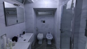 Kylpyhuoneessa on valkoinen pesuallas, kaksi wc-istuinta, bidee, peili ja suihkutila.