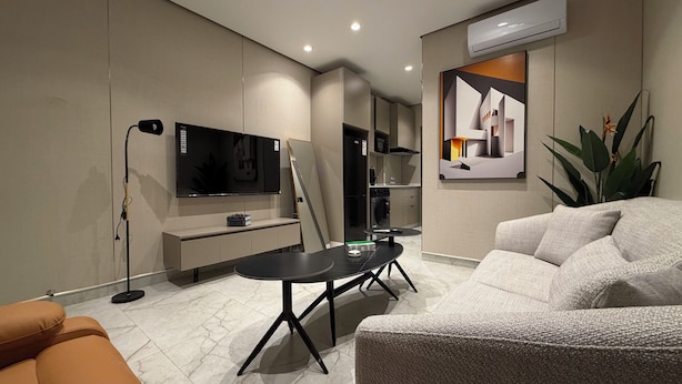 Een moderne woonkamer met een flatscreen-televisie, een bank, een salontafel en een eethoek.