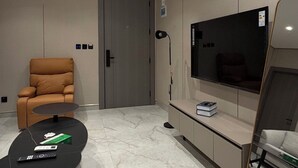 Een moderne woonkamer met een bank, een televisie, een salontafel en een deur.
