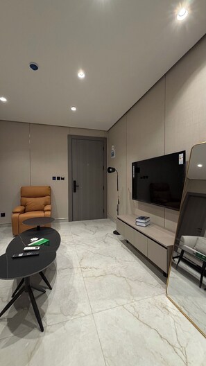 Ein modernes Wohnzimmer mit einer Couch, einem Fernseher, einem Couchtisch und einer Tür.