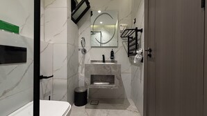 Een moderne badkamer met een marmeren wastafel, een spiegel, een handdoekhouder en een prullenbak.
