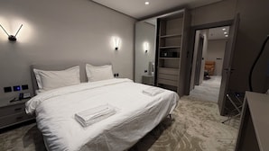 Een moderne hotelkamer met een groot bed, bedlampjes, een kledingkast en een bureau met telefoon.