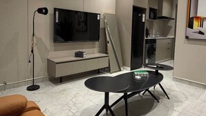 Een moderne woonkamer met een flatscreen televisie, een bank, een salontafel en een eethoek.