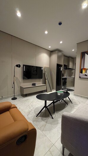 Ein modernes Wohnzimmer mit Flachbildfernseher, einer Couch, einem Couchtisch und einem Essbereich.