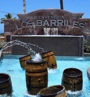 A pool with wooden barrels and a sign that reads 'BIENVENIDOS LOS BARRILES.' - Glamping Uno los Barilles (Los Barriles)