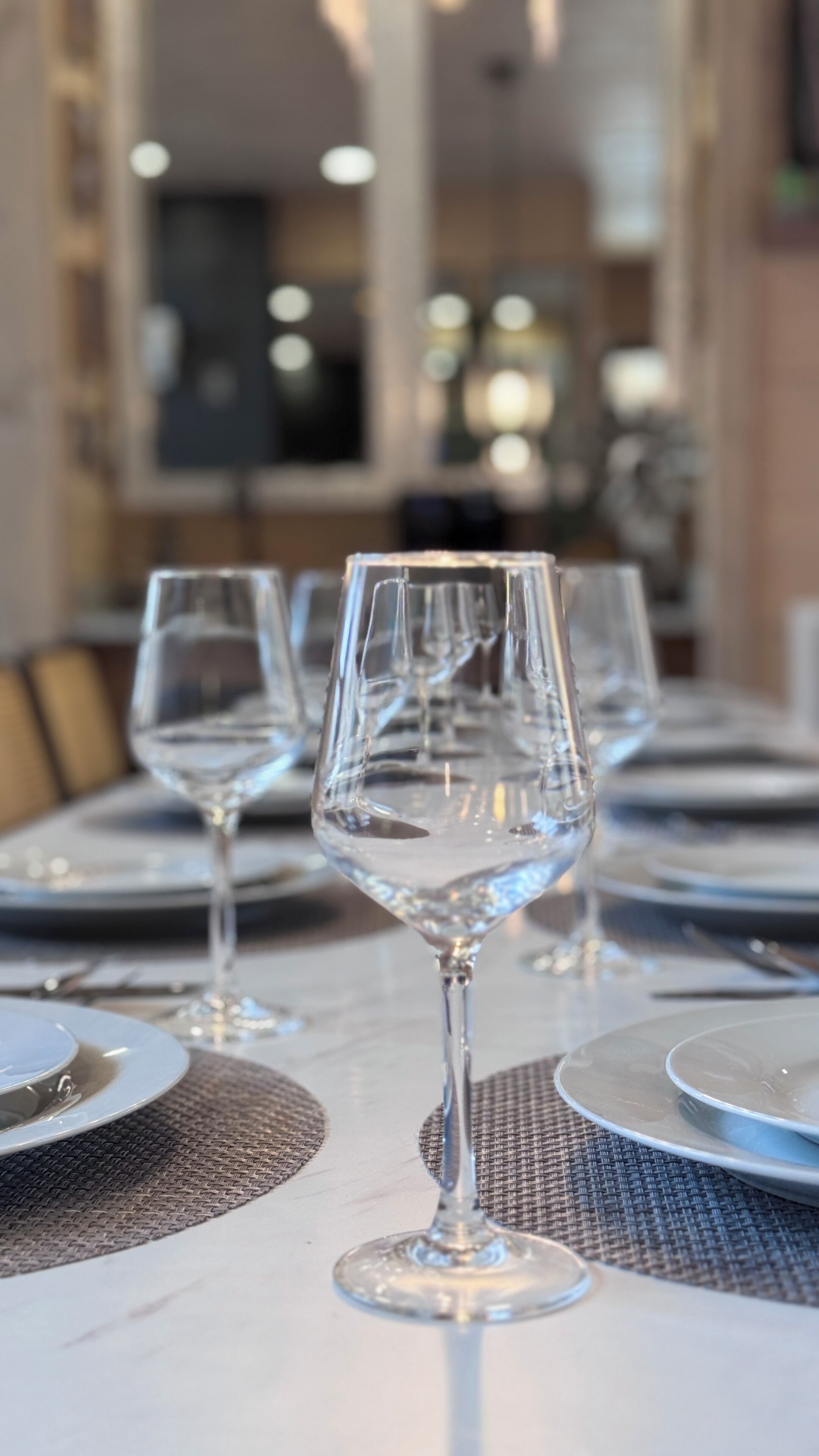 A dining table with empty wine glasses and plates, indicating a prepared table for guests.