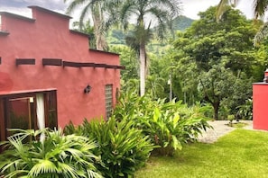 A red building with a small window and a door, surrounded by lush greenery and palm trees. - Luxury villa in Bolombolo • Pool, views and comfort (Bolombolo)