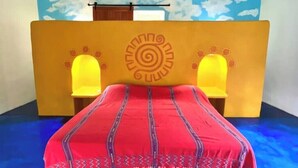 Una habitación con una cama, un mural en la pared y dos lámparas de pared.