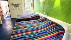 Una habitación con dos camas, una pared verde, una ventana y una puerta.