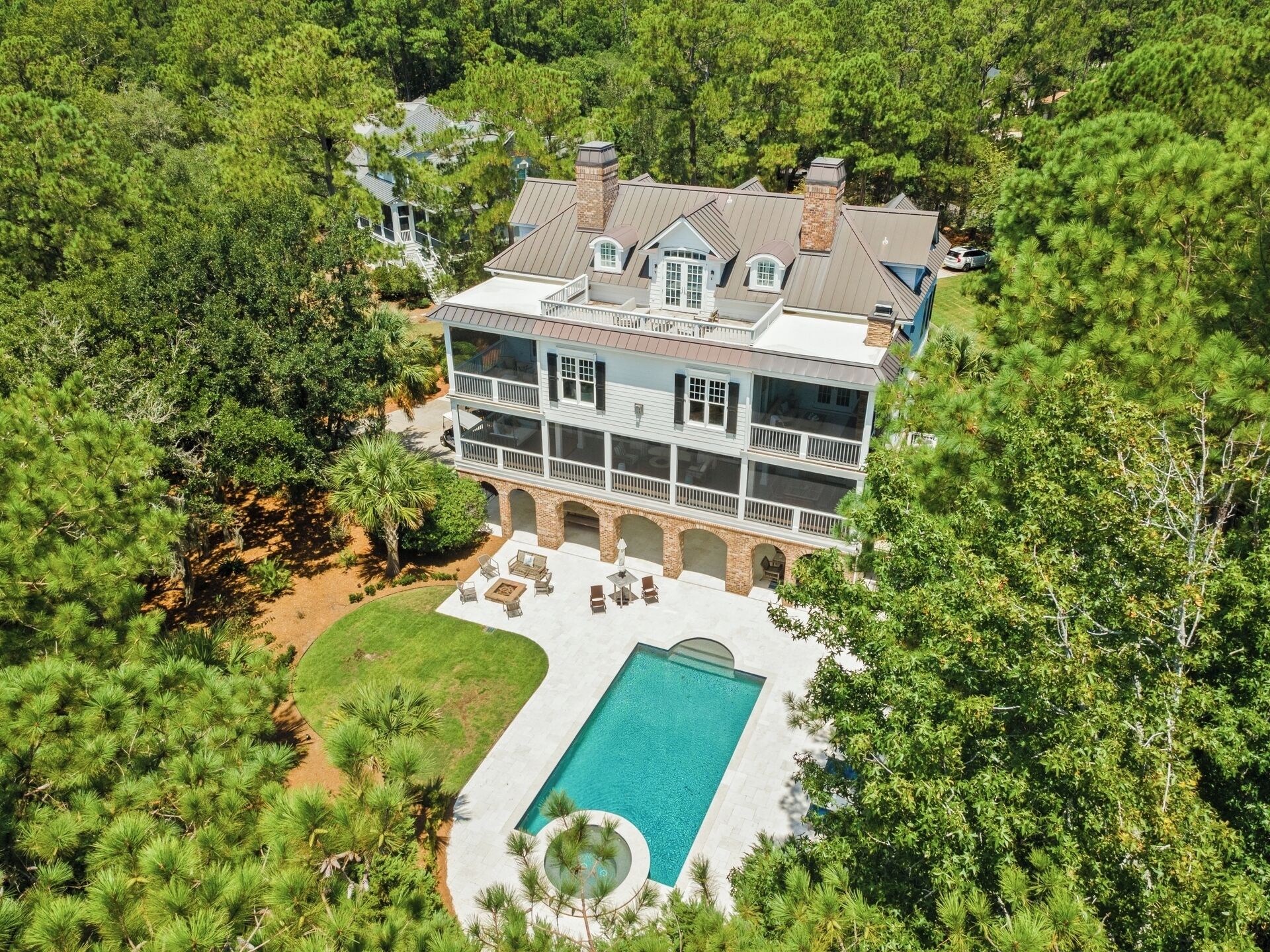 A large two-story house with a swimming pool, surrounded by dense trees.