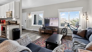 Una sala de estar moderna con un sofá, una mesa de centro, un televisor y una bicicleta al fondo.